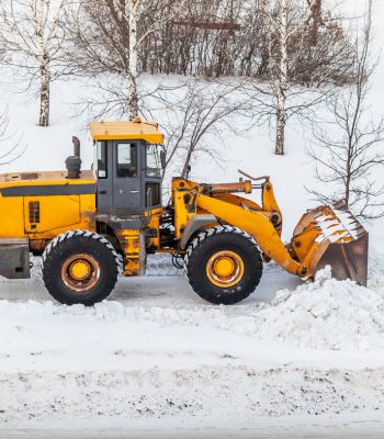 Snow clearing. Tractor clears the way after heavy snowfall. A large orange tractor removes snow from the road and clears the sidewalk. Cleaning roads in the city from snow in winter.