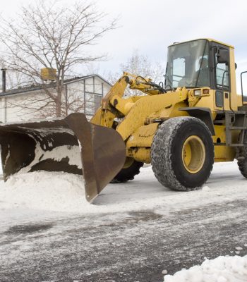 "Bulldozer or front end loader scrapes off snow and ice from neighborhood in Denver, Colorado"